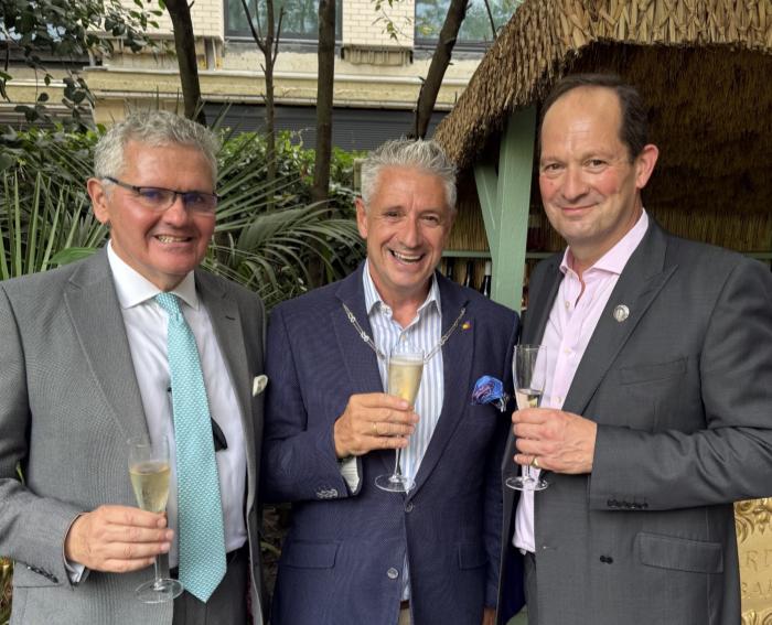 Three members with glasses of champagne in the garden of the Goring